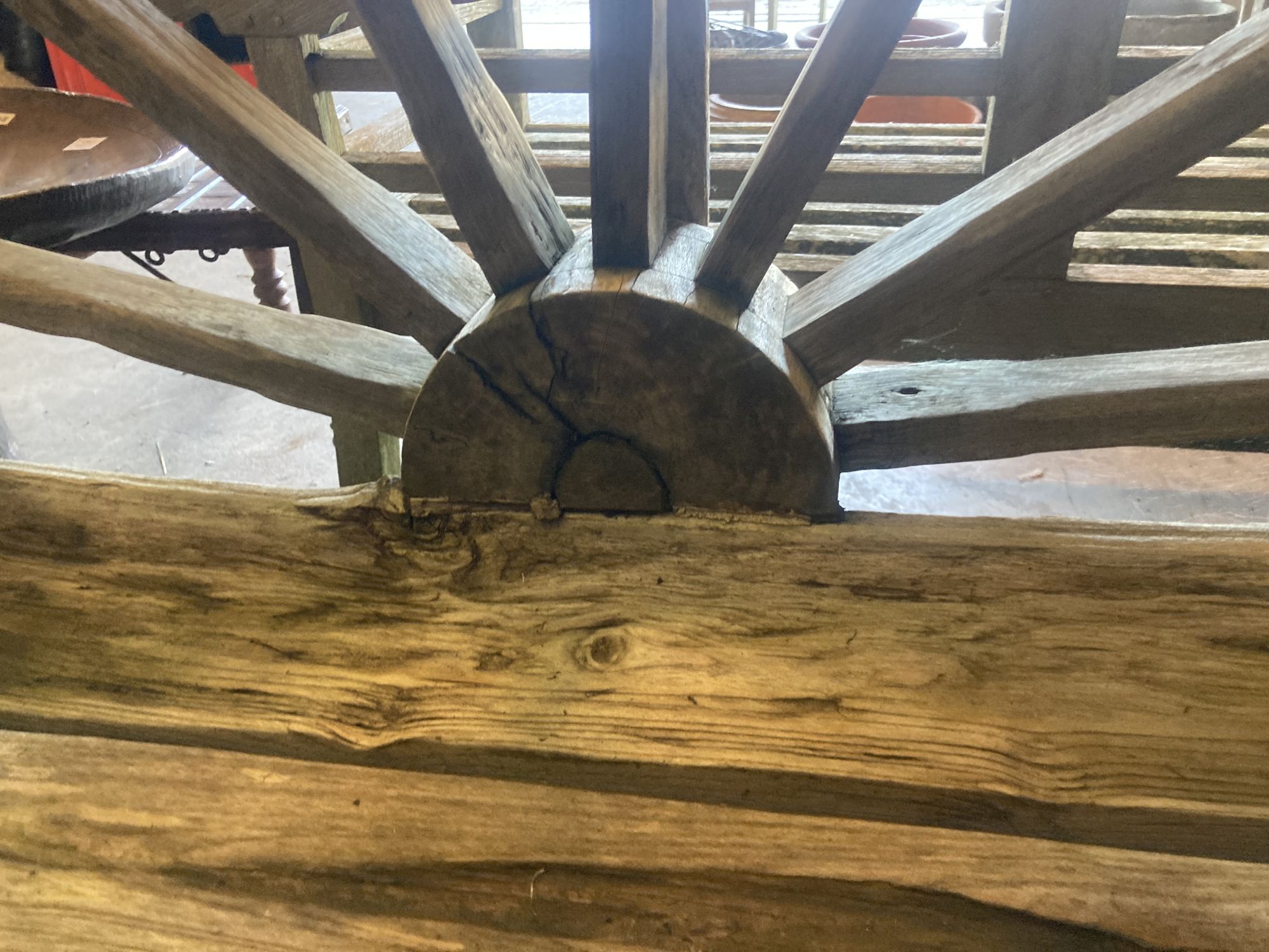 A weathered hardwood cartwheel garden bench, width 140cm depth 70cm height 116cm